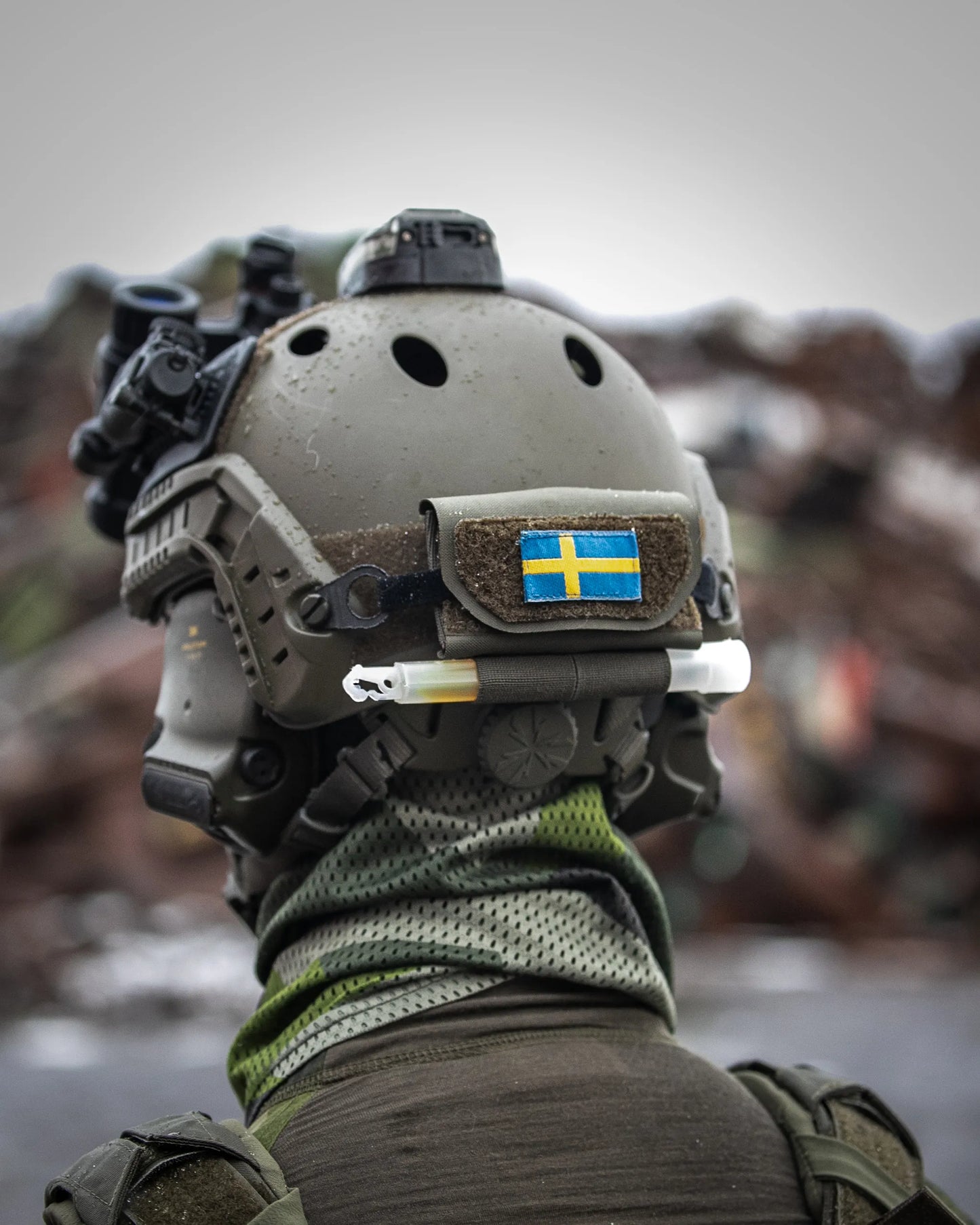 AXIS motviktsficka i Ranger Green, monterad på baksidan av en stridshjälm för att balansera NVG. AXIS är utrystad med svensk falgga och en lightstick.