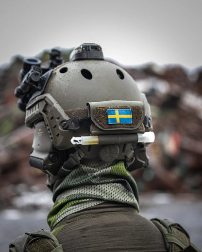 AXIS motviktsficka i Ranger Green, monterad på baksidan av en stridshjälm för att balansera NVG. AXIS är utrystad med svensk falgga och en lightstick.